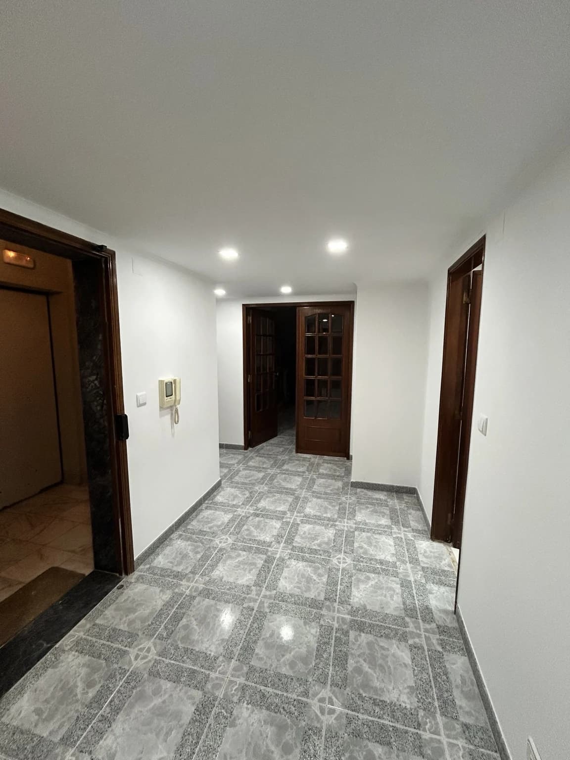 Corredor interior finalizado com pintura, pavimento e iluminação embutida
